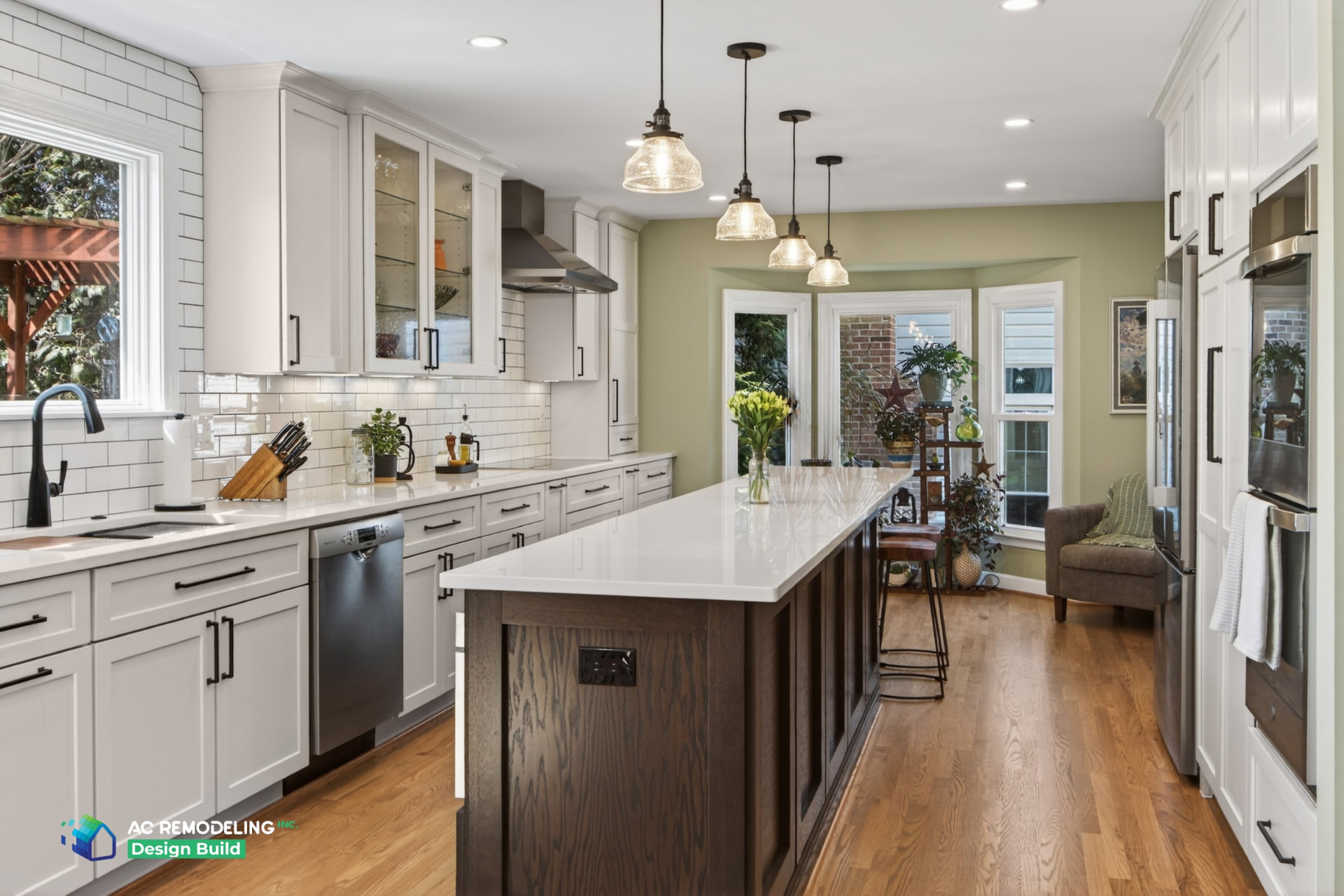 Bright galley kitchen with white shaker cabinetry, subway tile backsplash and long stained-oak island with white quartz top