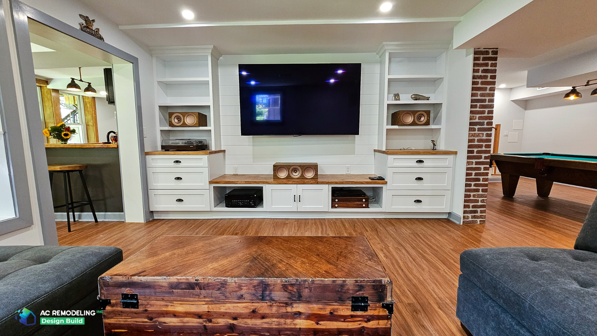 Luxe entertainment basement retreat with a wall-mounted TV, white built-in cabinetry and warm wood counters