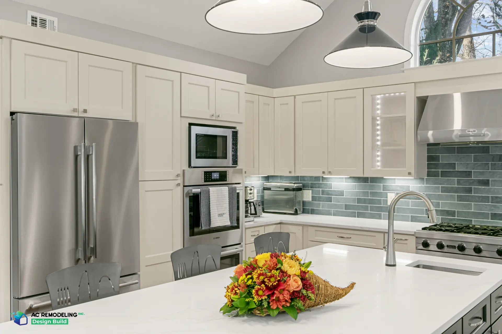 Cream cabinetry with double wall ovens and lit glass-front uppers
