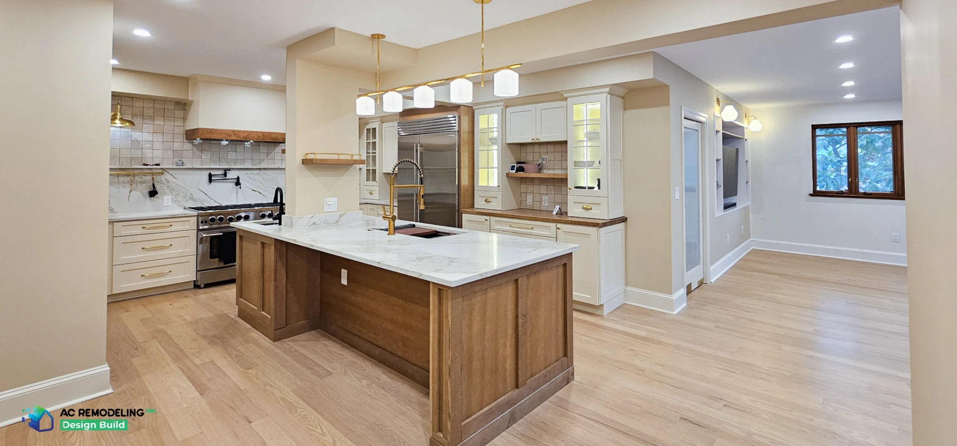 Remodeled kitchen with white oak island, marble countertops and brass pendants