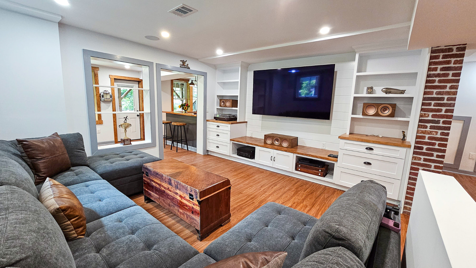 Finished basement with built-in media wall, exposed brick and sectional seating