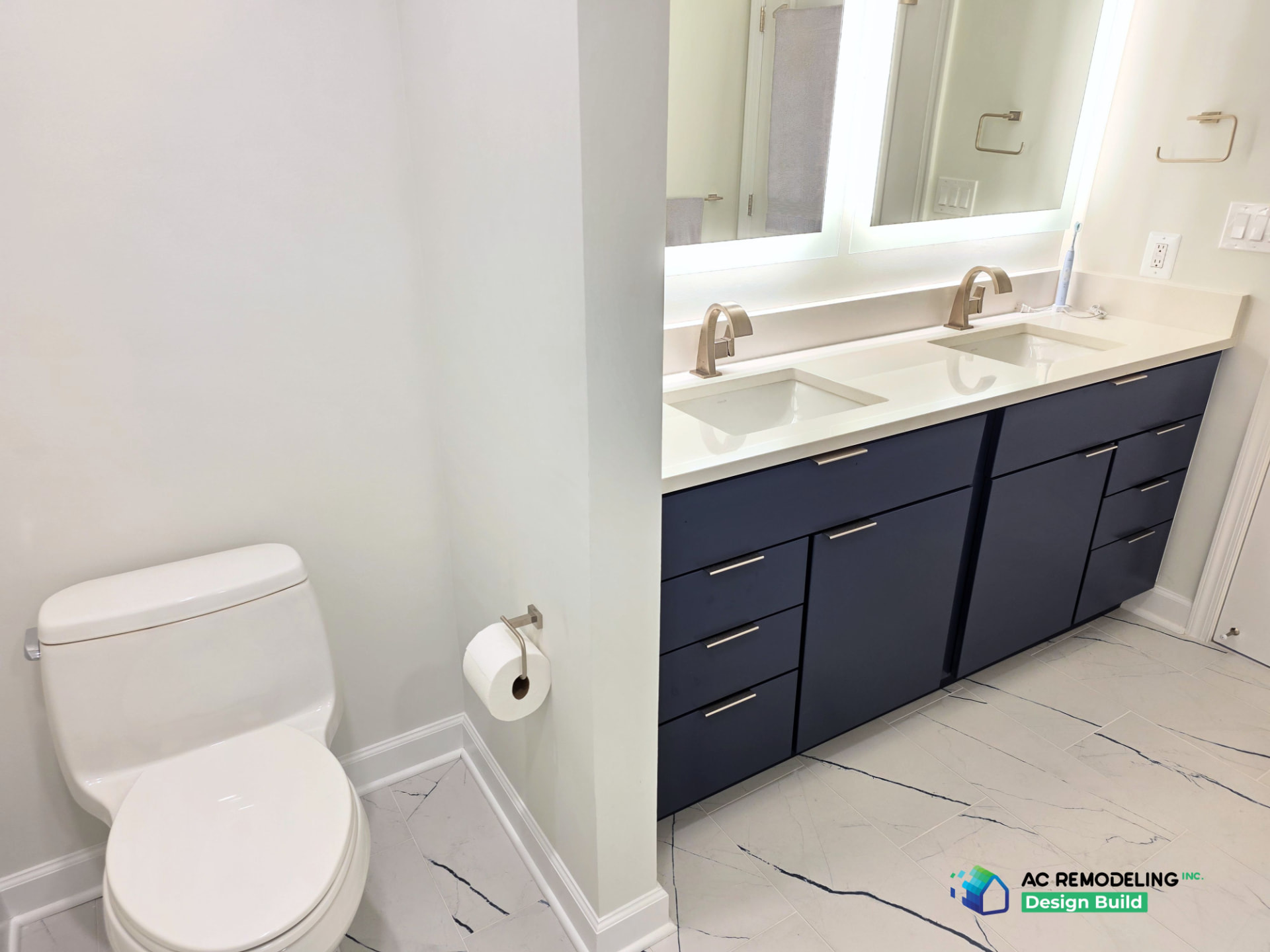 Bathroom with navy double vanity, backlit mirrors and marble tile floor