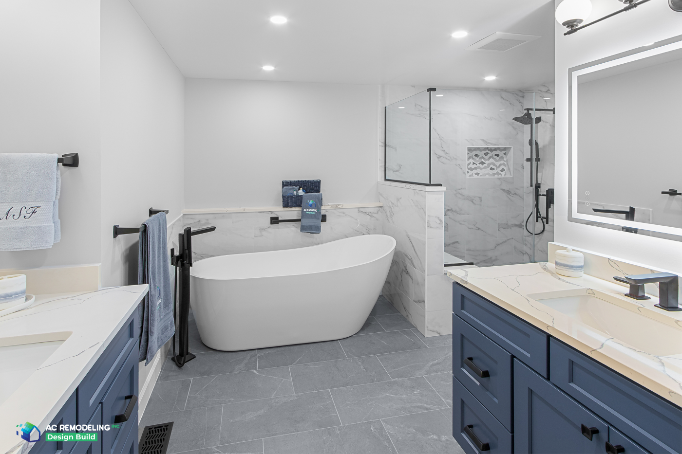 Primary bath with freestanding soaking tub, navy double vanities and glass shower