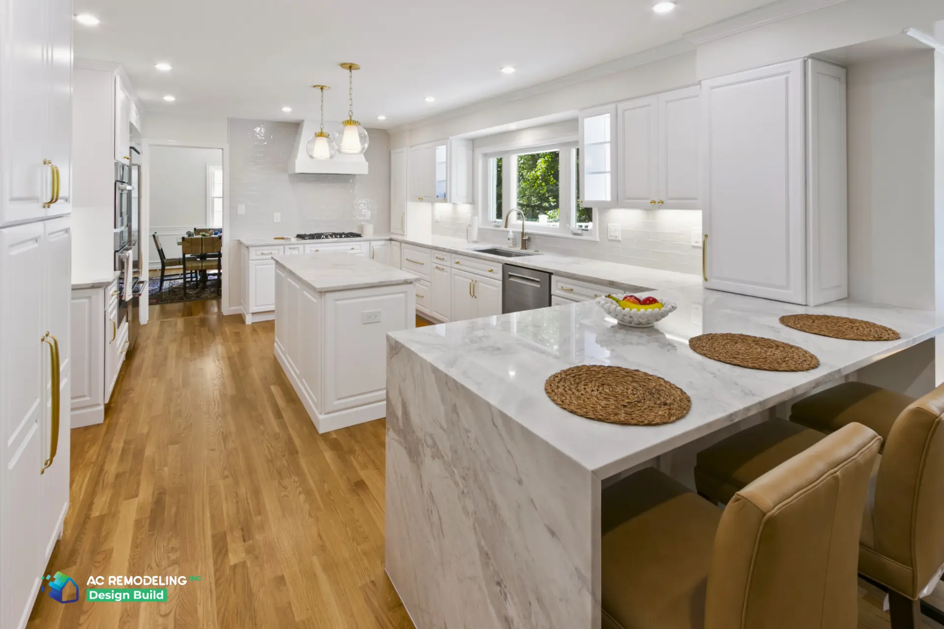 Open white kitchen with breakfast bar seating and glass pendant lights