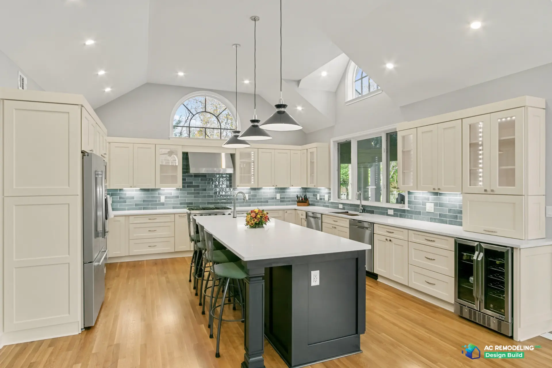 Vaulted white kitchen with cream shaker cabinetry, blue-green glass subway backsplash and a charcoal island with quartz top