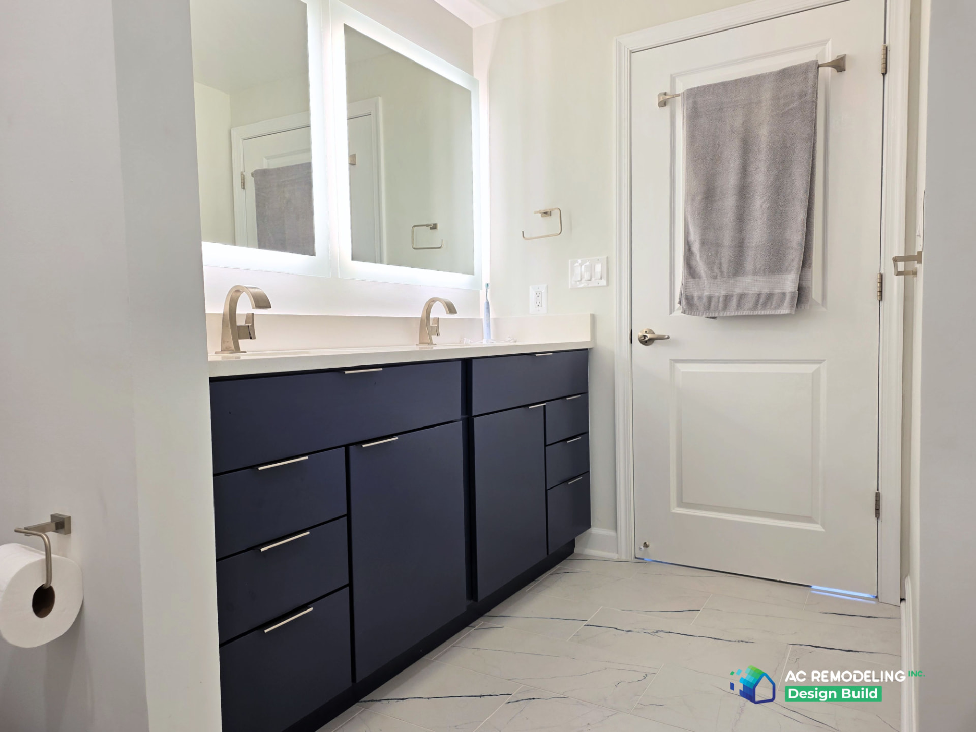 Navy slab double vanity with white quartz counter, brushed nickel faucets and backlit mirrors