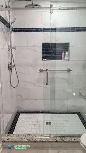 Stylish shower with a custom sliding door, accented by a luxurious rain shower head, handheld spray, and a convenient shower niche for all your bathing needs.